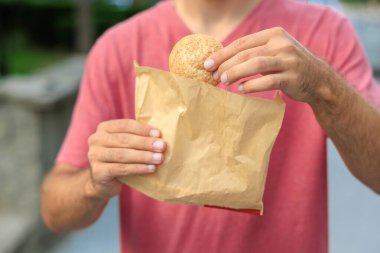 Adamın elinde mini ekmek, atıştırmalık ve fast food konsepti var. Bulanık arkaplan ve metin için kopyalama alanı olan ellere seçici odak.