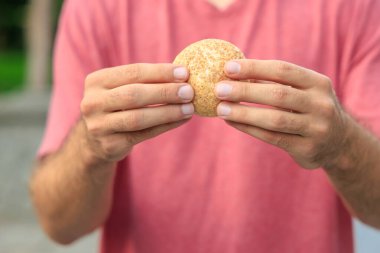 Adamın elinde mini ekmek, atıştırmalık ve fast food konsepti var. Bulanık arkaplan ve metin için kopyalama alanı olan ellere seçici odak.