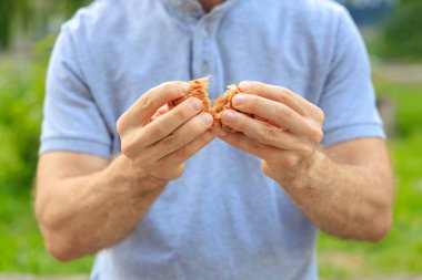 Bir adamın eli reçelli, abur cuburlu ve fast food konseptli tatlı bir hamur işi tutar. Bulanık arkaplan ve metin için kopyalama alanı olan ellere seçici odak.