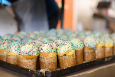 Bir tepsi kapkek ve üzerine de şeker serpiştirilmiş. Tepside bir sürü kek, fabrikada Paskalya pastası var.