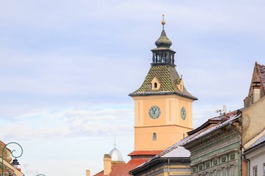 Üzerinde saat olan uzun bir saat kulesi. Gökyüzü bulutlu ve güneş görünmüyor.
