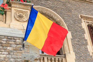 Romen ulusal bayrağı kentsel alanda tarihi taş inşaatında.