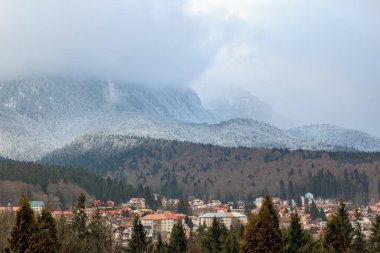 Kışın Romanya köyünün üzerinde karla kaplı dağlar.