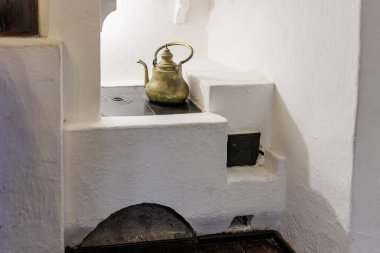 Köy ortamında geleneksel beyaz taş ocağın üzerinde antik pirinç çaydanlık..