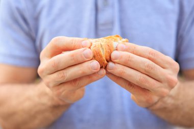 Bir adamın eli peynirli, abur cuburlu ve fast food konseptli mini puf böreği tutar. Bulanık arkaplan ve metin için kopyalama alanı olan ellere seçici odak.