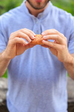 Bir adamın eli peynirli, abur cuburlu ve fast food konseptli mini puf böreği tutar. Bulanık arkaplan ve metin için kopyalama alanı olan ellere seçici odak.