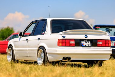 Güzel restore edilmiş bir BMW E30 M3 diğer klasik araçlar arasında bir otomotiv toplantısında sergilendi, bu ikonik modelin zamansız cazibesini vurguladı. 2 Temmuz 2023 Liadoveni Moldova.