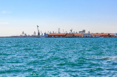 Arka planda küçük bir kasaba olan güzel mavi bir okyanus. Su sakin ve gökyüzü berrak. 8 Ağustos 2024 Selanik Yunanistan