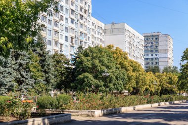 Güneşli havada Sovyet tarzı apartmanlı şehir parkı sahnesi. 9 Eylül 2024 Balti Moldova.