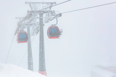 Kar manzaralı kırmızı teleferikler görüş mesafesi düşük. 15 Aralık 2024 'te Romanya.