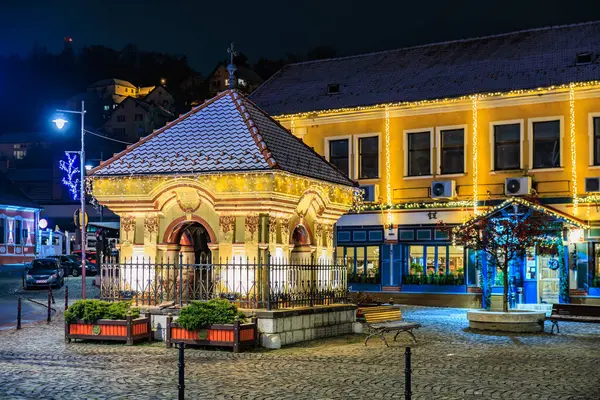 Çardağı ve çeşmesi olan küçük bir avlu. Çeşme aydınlandı ve çardak ışıklarla süslendi. 13 Aralık 2024 Brasov Romanya