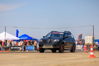 Siyah bir araba, bir kalabalık tarafından izlenen bir pistte gidiyor. Araba kırmızı ve beyaz bir iple çevrilidir. 2 Temmuz 2023 Liadoveni Moldova