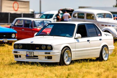 Güzel restore edilmiş bir BMW E30 M3 diğer klasik araçlar arasında bir otomotiv toplantısında sergilendi, bu ikonik modelin zamansız cazibesini vurguladı. 2 Temmuz 2023 Liadoveni Moldova.