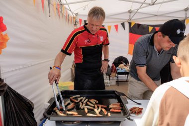 Gönüllüler, 19 Mayıs 2024 'te Balti Moldova' da düzenlenen Avrupa Günü boyunca Alman sosislerini hazırlayıp otantik Alman lezzetlerini ziyaretçilerle paylaşıyorlar.