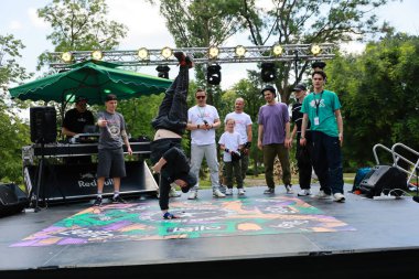 Genç erkek break dansçı çeşitli izleyicilerle açık hava hip-hop etkinliğinde amuda kalkıyor. 31 Mayıs 2024 Balti Moldova.