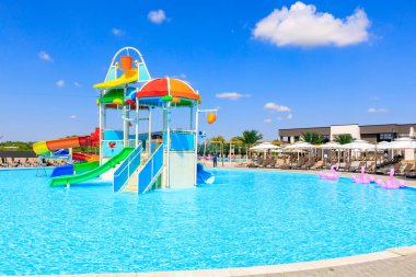 Su kaydırağı ve su sıçrama yastığı olan bir havuz. Su mavi ve gökyüzü berrak. 8 Haziran 2024 Balti Moldova