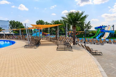 Havuzu ve bir sürü şezlongu olan bir plaj. Sandalyeler yayılmış ve gölge sağlayan şemsiyeler var. 8 Haziran 2024 Balti Moldova