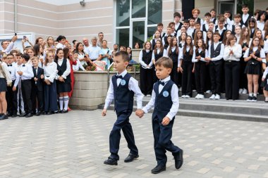 Okul törenine katılan iki beyaz üniformalı genç çocuk. 2 Eylül 2024 Balti Moldova.