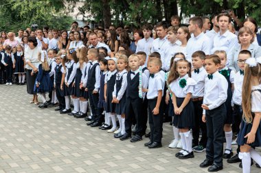 Bir grup beyaz çocuk ve yetişkin resmi kıyafetlerle okul etkinliğinde. 2 Eylül 2024 Balti Moldova.