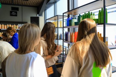 Genç beyaz kadınlar modern bir dükkandan saç bakım ürünleri alıyorlar. 18 Eylül 2024 Balti Moldova.