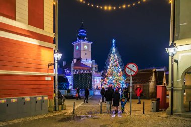 Kasaba meydanında bir Noel ağacı parlıyor. İnsanlar etrafta dolanıyor ve festival atmosferinin tadını çıkarıyorlar. 13 Aralık 2024 Brasov Romanya