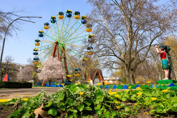 Dönme dolabı ve kadın heykeli olan bir park. Park yeşillik ve çiçeklerle dolu. 1 Nisan 2024 Balti Moldova