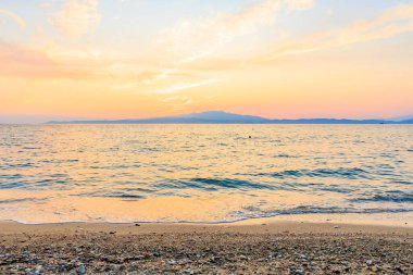 Okyanus sakin ve gökyüzü güzel turuncu bir renktir. Güneş batıyor, huzurlu ve huzurlu bir atmosfer yaratıyor.