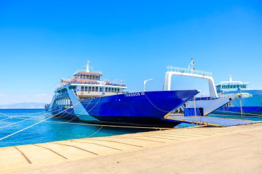 Yan taraftaki mavi bir tekne rıhtıma yanaştı. Su sakin ve gökyüzü berrak. 7 Ağustos 2024 Thassos 'tan Keramoti Yunanistan feribotu