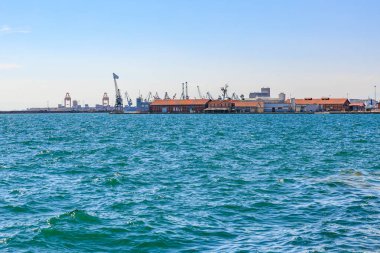 Arka planda küçük bir kasaba olan güzel mavi bir okyanus. Su sakin ve gökyüzü berrak. 8 Ağustos 2024 Selanik Yunanistan