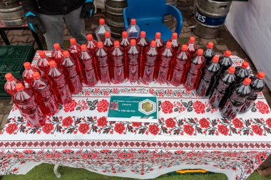 Açık hava pazarındaki gül desenli masada kırmızı ve siyah şarap çeşitleri. 15 Şubat 2024 Balti, Moldova.