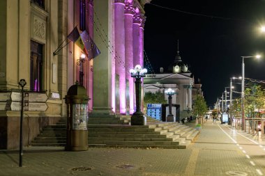Aydınlatılmış tarihi bina ve bayraklarla Avrupa gece caddesi manzarası. 9 Ekim 2024 Chisinau Moldova.