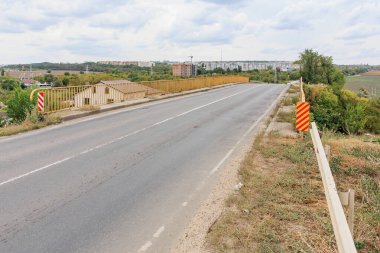 Şehir manzarası ve bulutlu gökyüzü olan bir köprüdeki boş şehir yolu.