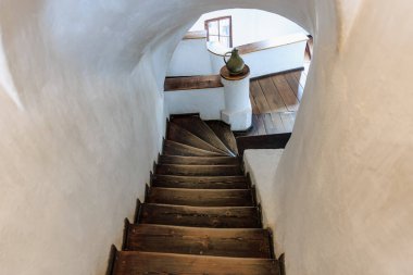 Tarihi binada beyaz duvarları ve antika sürahileri olan ahşap bir merdiven..