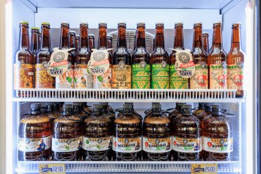 Buzdolabında sergilenen çeşitli içecekler: şişe bira ve elma şarabı seçimi. 1 Şubat 2024 Balti Moldova.