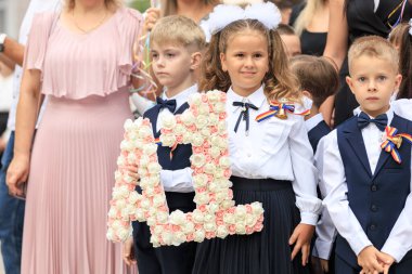Genç beyaz çocuklar okulun açılışını çiçeklerle kutluyorlar. 2 Eylül 2024 Balti Moldova.