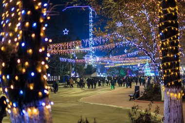 Bayram gecesi: Kalabalık renkli tatil ışıklarıyla aydınlatılmış parkın tadını çıkarıyor. 20 Aralık 2024 Balti Moldova.