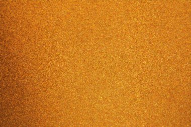 Kumlu dokuya sahip sarı bir yüzeye yakın çekim. Yüzey küçük, düzensiz tahıllarla kaplı.