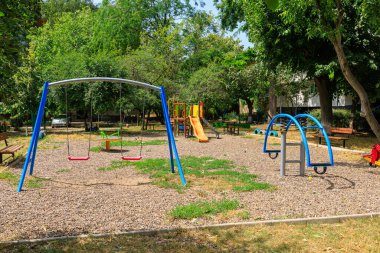 Yeşillik içinde salıncaklı, kaygan ve tırmanma çerçeveli renkli bir oyun alanı. 26 Temmuz 2023 Beltsy Moldova.