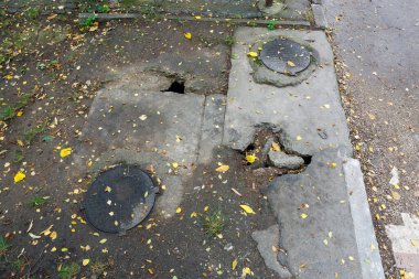 Rögar kapakları ve çatlakları olan yıpranmış şehir kaldırımları. 20 Ekim 2023 Beltsy Moldova.