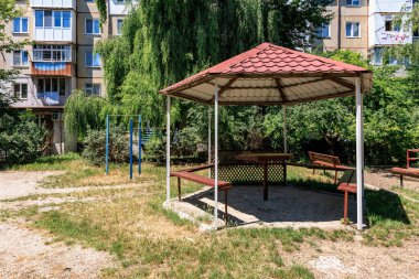 Yeşil şehir parkında apartmanlı kırmızı çatılı çardak. 12 Haziran 2024 Balti Moldova.