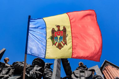 Moldova ulusal bayrağı anma yerinde mavi gökyüzüne sembolik amblemle dalgalanıyor. 18 Haziran 2024 Balti Moldova.