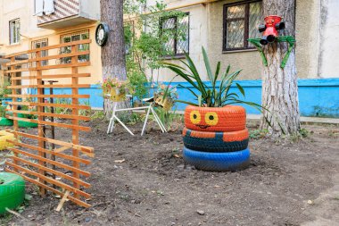Boyanmış lastik ekicileri ve kırsal ahşap çitleri olan yaratıcı bahçe dekoru. 17 Temmuz 2024 Balti Moldova.
