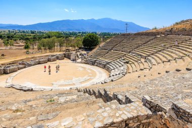 Etrafında bir grup insanın yürüdüğü büyük taştan bir amfi tiyatro. Sahne huzurlu ve huzurlu, insanlarla birlikte. 7 Ağustos 2024 Philippi Yunanistan