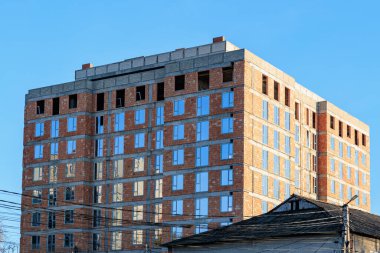 Mavi gökyüzüne karşı tamamlanmamış tuğla apartman.