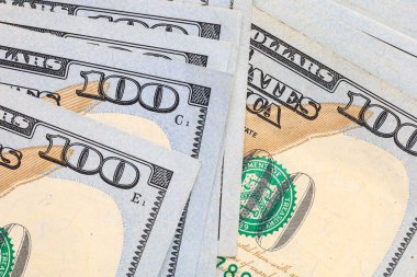 Mavi güvenlik şeridi ve Benjamin Franklin 'in portresini içeren 100 dolarlık banknotların yakın plan fotoğrafları..