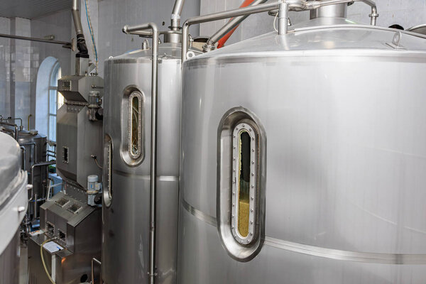 Modern brewery equipment with large stainless steel fermentation tanks.
