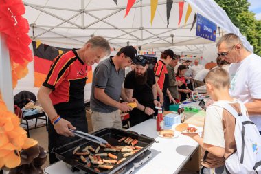 Alman gönüllüler 19 Mayıs 2024 'te Balti Moldova' da Avrupa Günü 'nde ızgara sosis pişiriyor ve otantik Alman mutfağını ziyaretçilerle paylaşıyor.