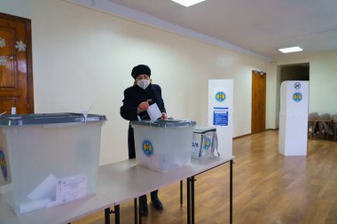 Seçimler sırasında oy kullanma merkezinde yaşlı beyaz bir kadın oy kullanıyordu. 19 Aralık 2021 Balti, Moldova.