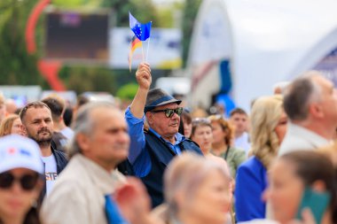 Kalabalığın içinde mavi bayrak taşıyan bir adam. Kalabalık çok farklı ve adam ilgi odağı, Avrupa Günü 'nü kutluyor. 19 Mayıs 2024 Balti Moldova