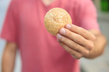 Adamın elinde mini ekmek, atıştırmalık ve fast food konsepti var. Bulanık arkaplan ve metin için kopyalama alanı olan ellere seçici odak.